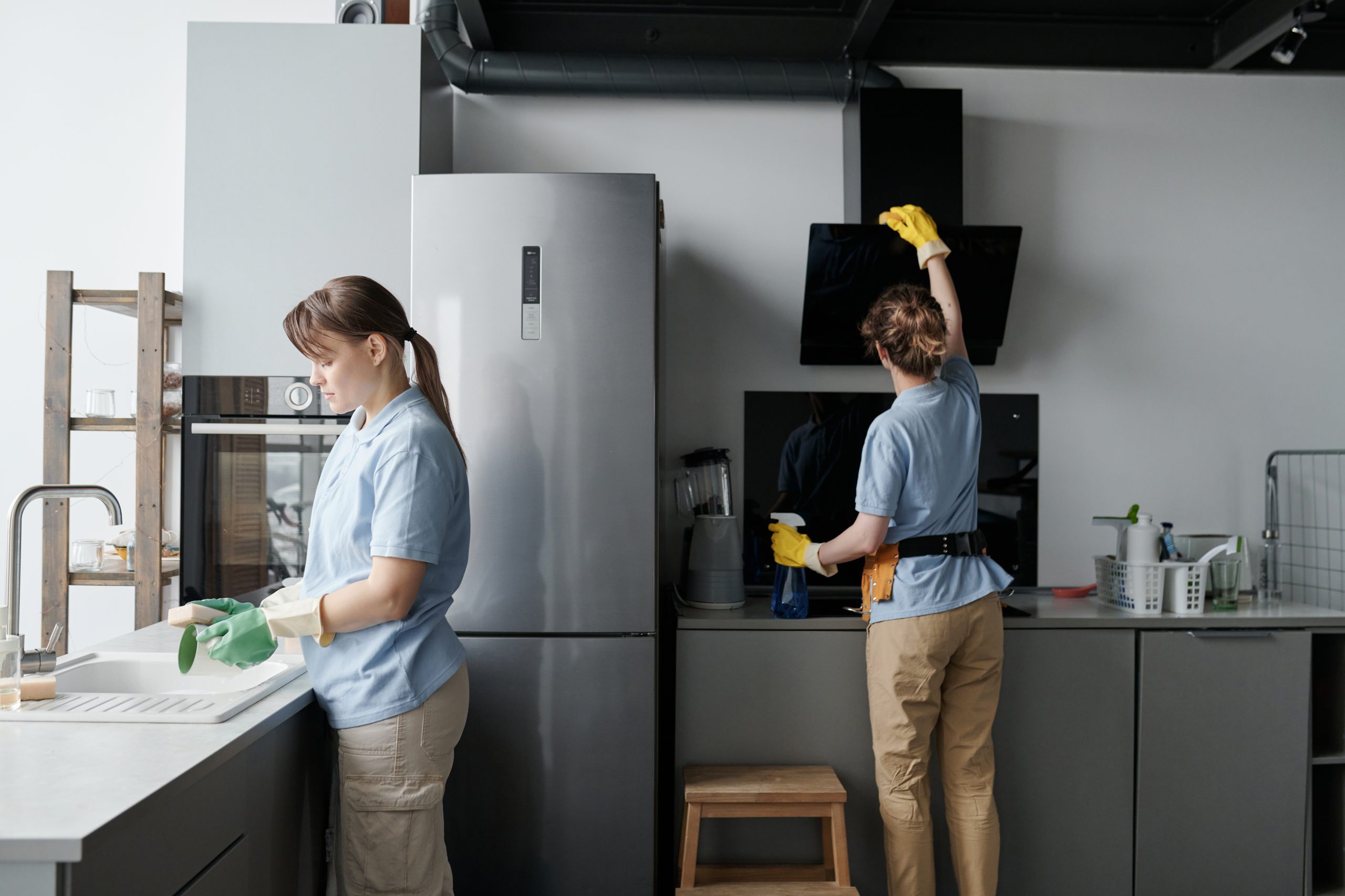 Professional cleaning workers wiping dust from furniture while doing housework in team in the kitchen